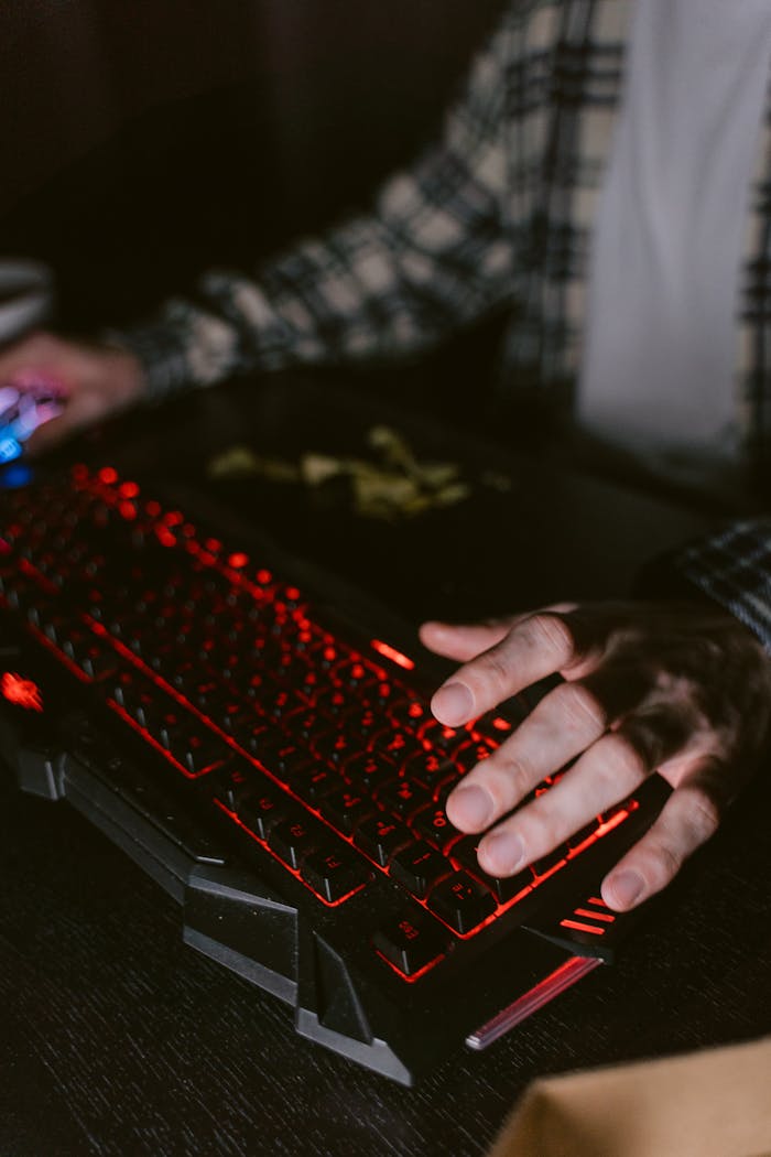 Close-up of hands using backlit mechanical keyboard, ideal for gaming and technology themes.