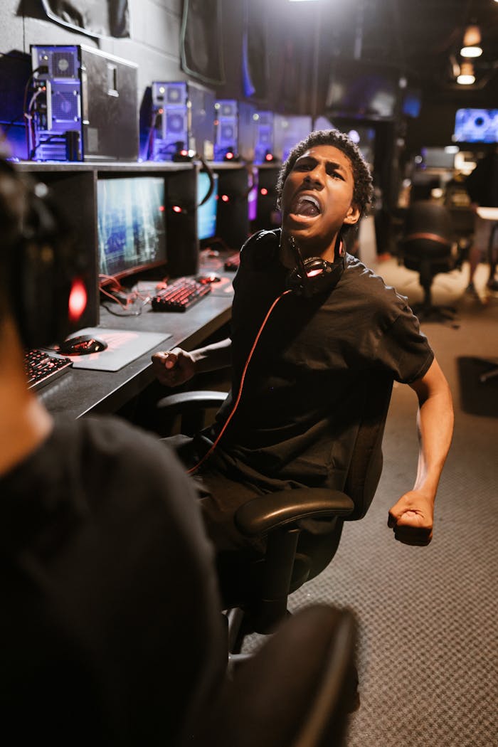 A man enthusiastically celebrating a gaming victory in a modern eSports arena.
